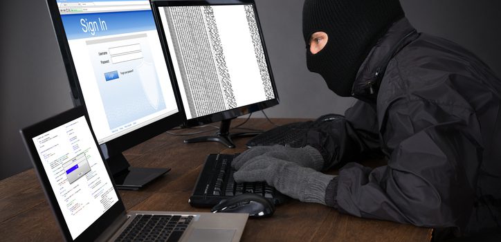 Hacker Wearing Balaclava Hacking Computers At Desk
