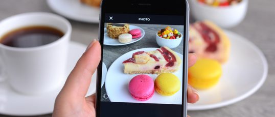 İstanbul, Turkey - January 26, 2016: Woman hands holding an Apple iPhone 6 and taking photos of a food with Instagram application. iPhone is a touchscreen smart phone produced by Apple Inc.